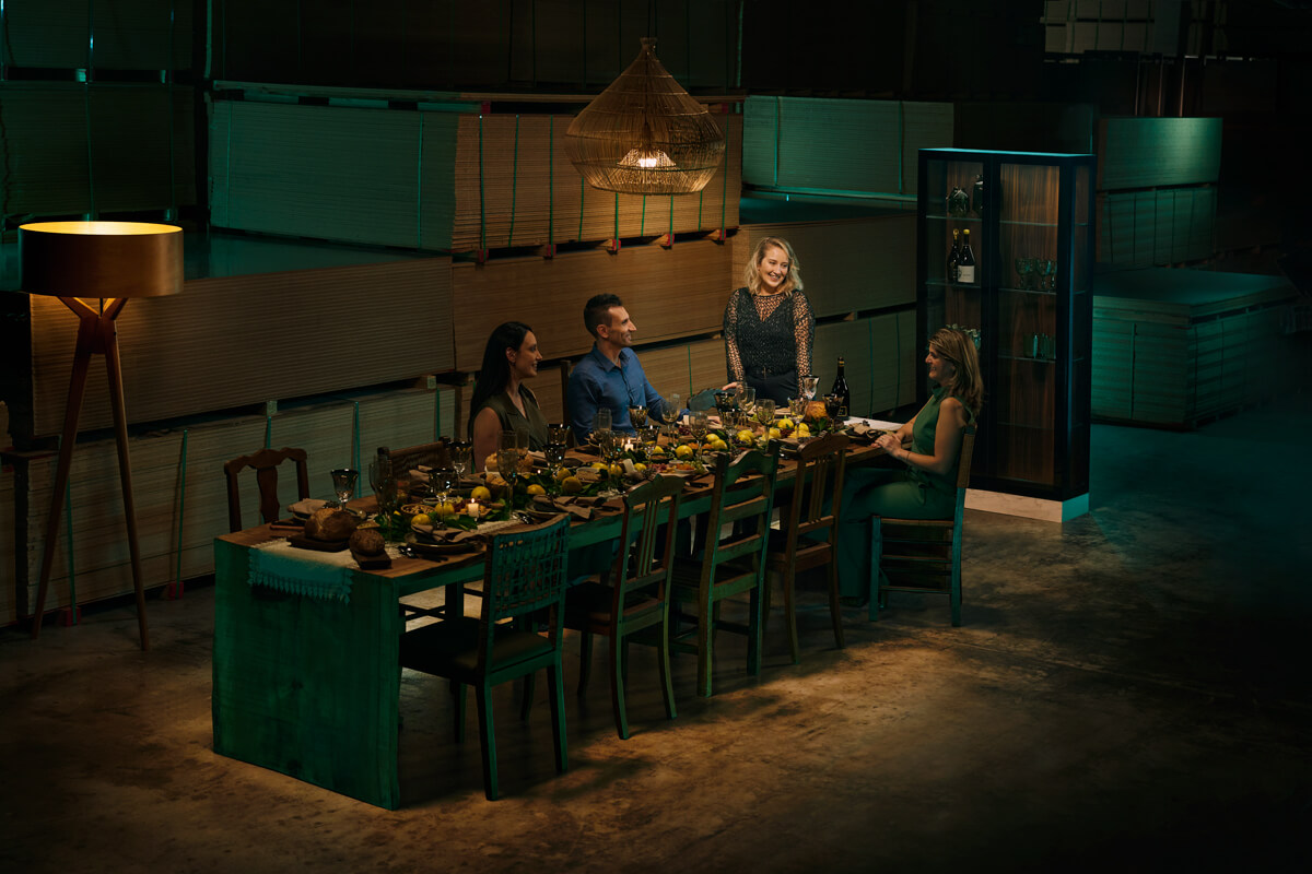 Grupo de pessoas desfrutando de um jantar elegante em uma mesa comprida em um armazém decorado - Evivva.
