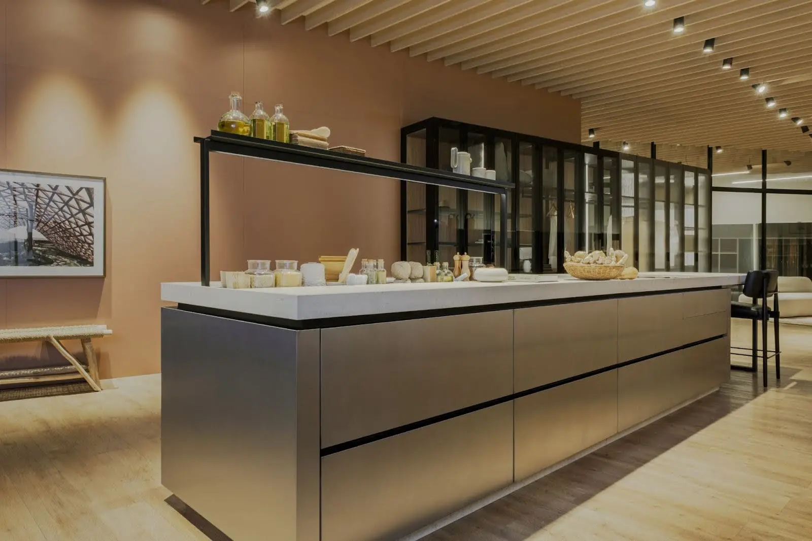 Cozinha moderna Evviva com design atemporal e estética elegante, ilha em inox com bancada minimalista, iluminação em ripas de madeira e detalhes funcionais sofisticados.